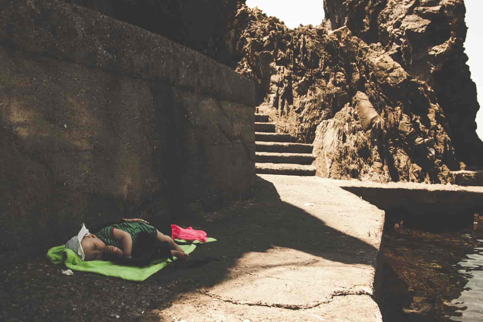 wypoczynek dziecka nad wodą w cieniu skał